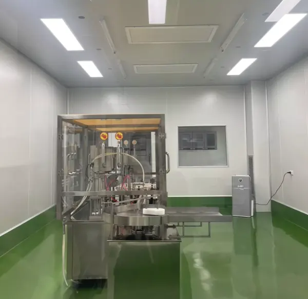 Abfüllmaschine aus Edelstahl in einem sauberen, weißen Reinraum mit grünem Boden und Deckenleuchten.