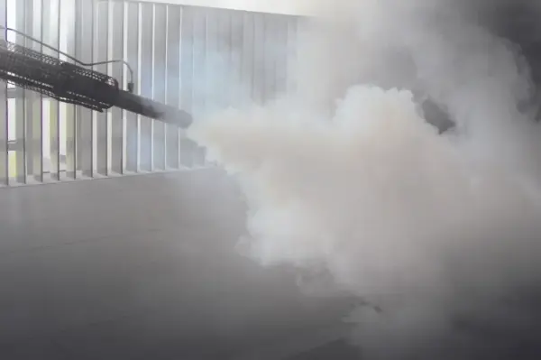 Eine Person sprüht Rauch mit Desinfektionsmittel in einem Tierstall angewendet wird.